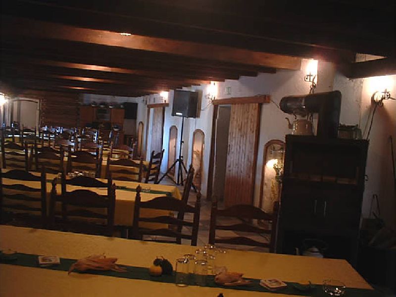 Langer, gedeckter Tisch im Saal des Partystalls; dahinter weitere Tafeln unter einer dunklen Holzbalkendecke, rechts ein alter Küchenschrank.