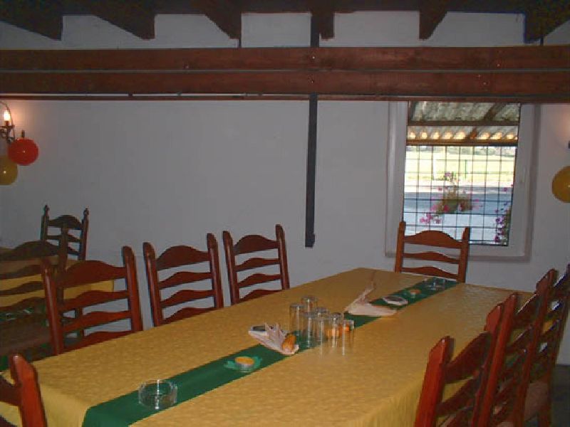 Gedeckter Tisch mit gelber Decke und grünem Läufer vor einem Sprossenfenster mit Blumenkasten.
